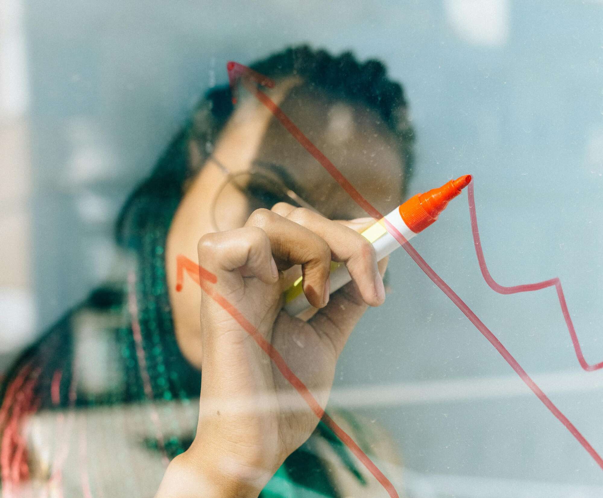Franchise Broker Woman drawing on window with red marker, drawing a stock market arrow graph